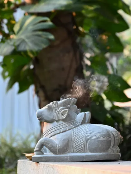A side view of the twin Nandi statue, with incense smoke drifting in the background, capturing a moment of peace and stillness.