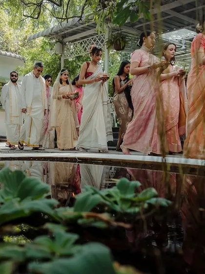 The bridal party makes a graceful procession by a lily pond, adding to the serene and elegant atmosphere of the wedding.