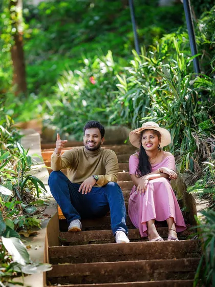 A casual and relaxed shot of a couple sitting on steps in a lush, green environment.