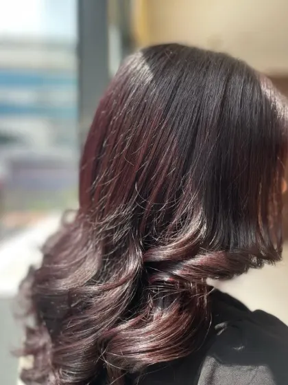 A beautiful demonstration of a soft, romantic hairstyle with bouncy curls and a hint of burgundy color. This look is perfect for parties and evening events.