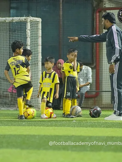 A coach gives directions to a group of young players, ensuring they understand the drill. Clear instruction is fundamental to my coaching style.