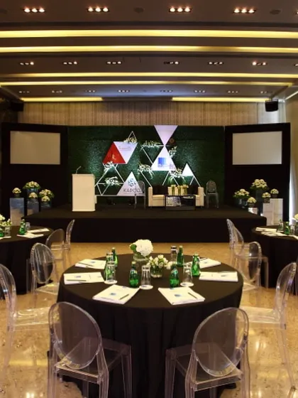 A conference setup with a custom stage backdrop and round-table seating. This flexible arrangement facilitates both presentations and group discussions, and our team ensures all technical and catering needs are flawlessly met.