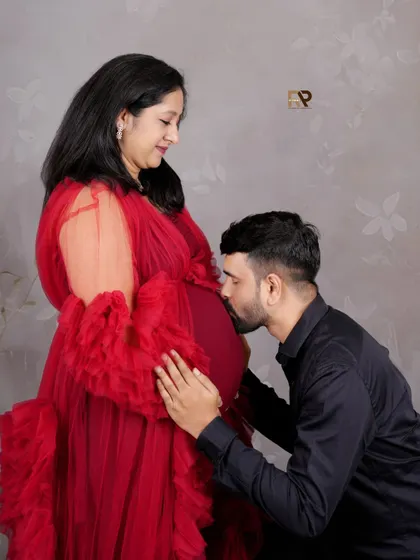 A classic pose filled with love. The dad-to-be gently kisses the baby bump, a timeless expression of his excitement and connection to their unborn child.