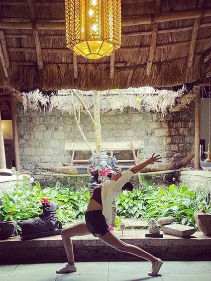 A flowing warrior pose in a tranquil courtyard in Kerala. With a Ganesha statue watching over, this practice becomes a moving meditation, connecting us to the spiritual heritage of the land.