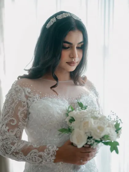 A beautiful portrait of a Christian bride holding her bouquet of white roses, bathed in soft window light.