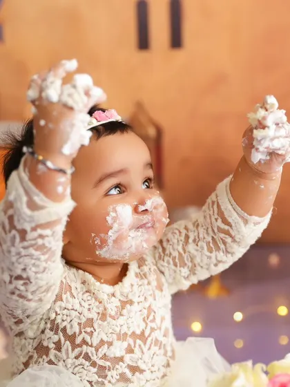 Arms up in celebration, this baby girl is having the best time during her cake smash photoshoot.