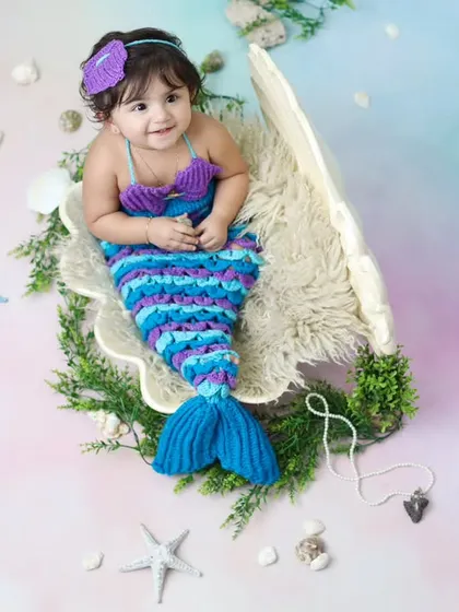 This shot captures a sweet, smiling expression from our little mermaid. The setup includes starfish, shells, and greenery to create a beautiful underwater grotto feel.