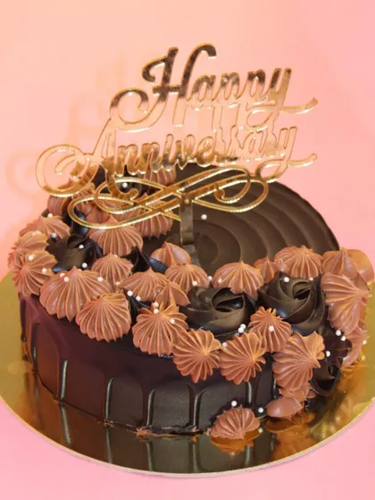 An elegant chocolate anniversary cake. The rich dark chocolate is complemented by delicate piping and a golden "Happy Anniversary" topper.