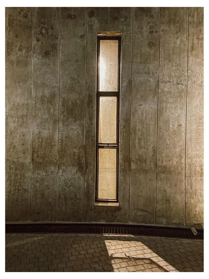 The play of light and shadow on a concrete wall, a simple detail that reveals the texture and materiality of the building.