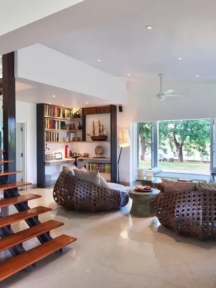 This view of the Aishbagh living area shows the open, flowing nature of the space. The cantilevered staircase adds a strong architectural element, while the mix of modern and traditional furniture creates a comfortable, global aesthetic.