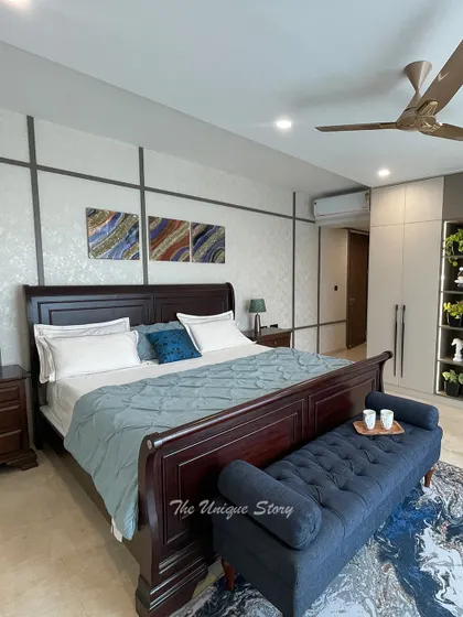 A wide shot of the elegant bedroom, showcasing the balance between the classic wooden bed and the modern, clean-lined wardrobe. The blue and earthy tones create a calm and sophisticated atmosphere.