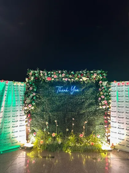 A lush green photo wall with a "Thank You" neon sign, created for a corporate appreciation event at Le Méridien, Gurgaon.