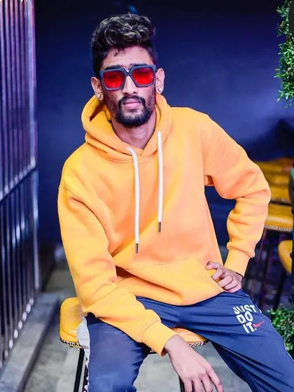 A posed shot in a yellow hoodie, showcasing my casual and confident style outside of the DJ booth.