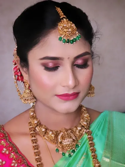 A gorgeous look for Pooja's baby shower. The focus is on her eyes, with a shimmery pink eyeshadow that makes them pop, paired with traditional gold jewelry and a bright green and pink saree.