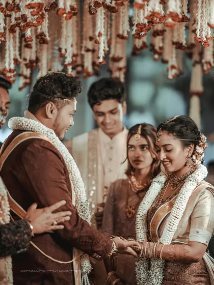 The joining of hands during the ceremony. This close-up shot focuses on the symbolic act of union, surrounded by the warm, festive atmosphere of the wedding.