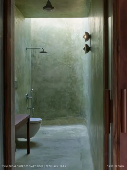 The bathroom at Villa Uma features green-hued plaster walls and a skylight that bathes the space in soft, natural light. The design turns a functional room into a serene, spa-like experience.
