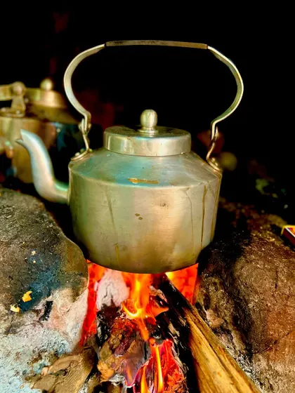 Even a simple cup of tea is given the traditional treatment. An aluminum kettle sits on a wood fire, showcasing our commitment to authentic preparation methods in every detail.