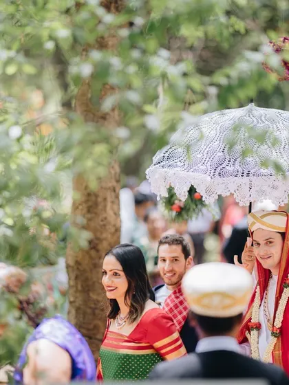 A groom, sheltered by a traditional Indian umbrella, makes his way to the wedding ceremony.