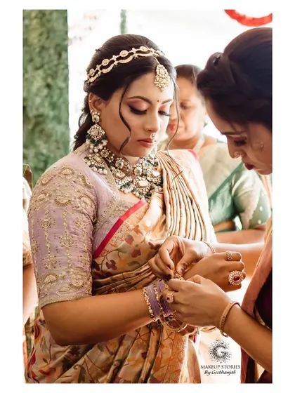A close up of Nidhi during her bangle ceremony. Her makeup is intricate and detailed, with a focus on her eyes, which are beautifully defined.