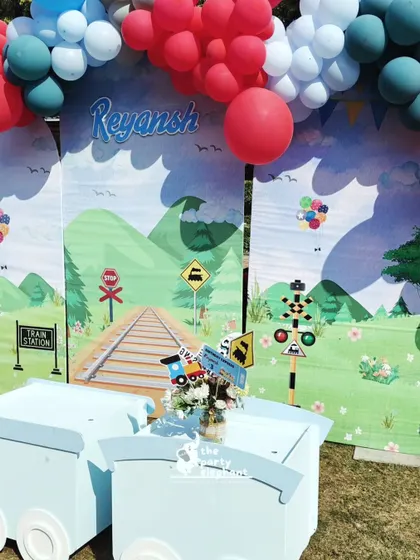 The centerpiece of the train party was this adorable setup featuring a custom backdrop of a railway track and landscape, with a light blue train prop for the kids to play in.