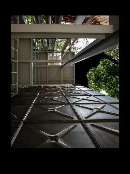 An upward view of the MAP facade at night, highlighting the texture of the pressed steel panels. This detail, inspired by common water tanks, connects the monumental building to an everyday object, grounding it in a local context.