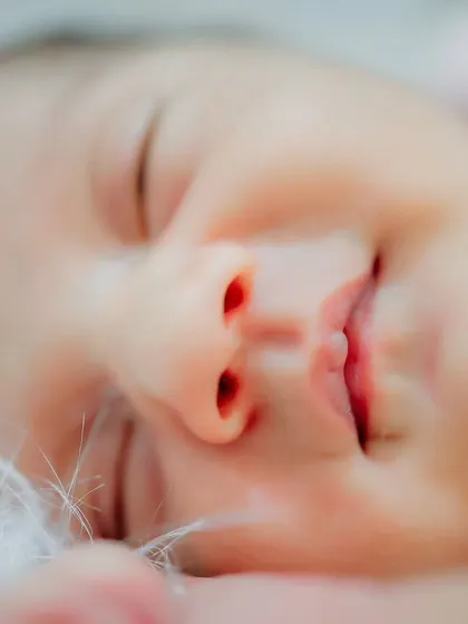 There is nothing more perfect than a newborn's sleepy smile. This macro shot focuses on the tiny, delicate features of a sleeping baby, from their little nose to their perfectly shaped lips, preserving the details you'll want to remember forever.