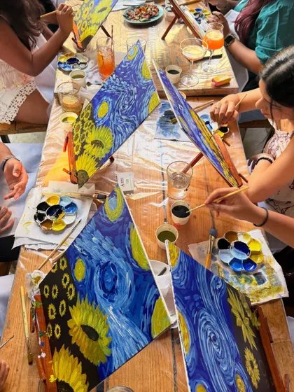 A top-down view of a table full of Starry Night paintings in progress. The collective creativity is inspiring.