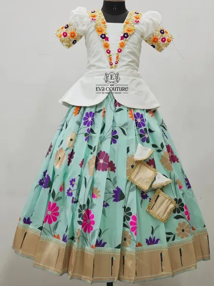 A modern floral lehenga with a white peplum top. The blouse has unique floral embroidery along the neckline, and the light blue skirt has a scattered floral print.
