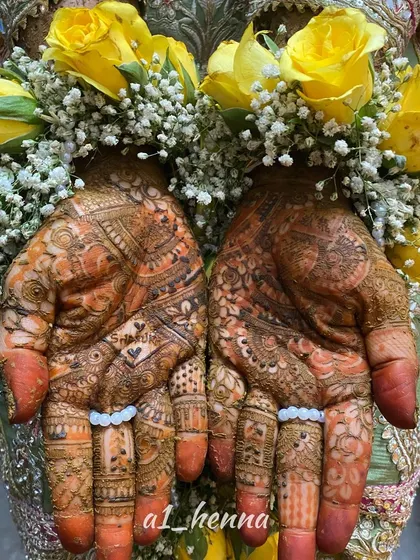 A beautiful shot of bride Daniya's hands, adorned with fresh flowers that complement her intricate bridal mehndi.