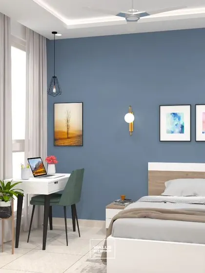 A peaceful bedroom with a cool blue accent wall. The space is efficiently designed with a floor-to-ceiling white wardrobe and a compact study desk by the window.