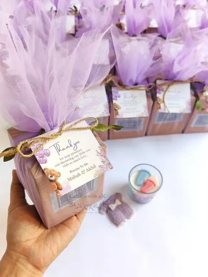 Holding one of the finished baby shower gift boxes for Mahak and Akhil. The lilac net wrapping and custom teddy bear thank you card perfectly match the theme, showing my attention to detail in packaging.