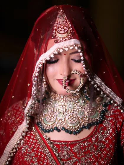 A stunning close-up bridal portrait. The focus is on the bride's flawless makeup, her intricate jewelry, and her serene, downward glance.
