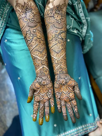 A complete view of a bride's henna, showing how the patterns on both hands work together. The design is a beautiful example of traditional Indian bridal art.
