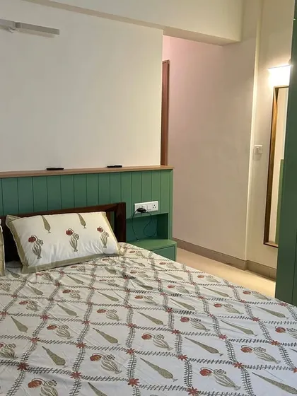 When the bedroom is a dream, but sleep is still stuck in traffic. A cozy bedroom with a green-paneled headboard and matching wardrobe.