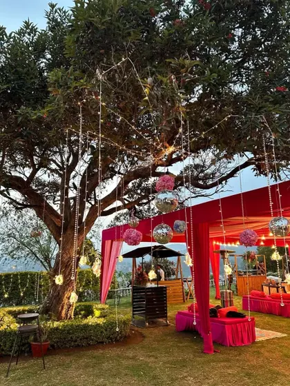 We love creating vibrant, festive spaces. This outdoor Sangeet features a large tree decorated with hanging disco balls and floral arrangements over a brightly colored tent, ready for a party.