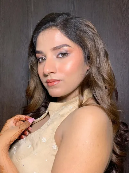 A close-up portrait where the client's softly curled hair adds to the overall glowing and dewy makeup look.