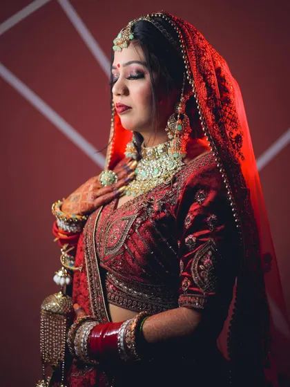 A dramatic portrait using red lighting to match the bride's lehenga, creating a bold and cohesive look.