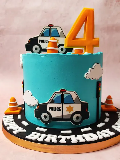 We create a fun and exciting scene with this police car themed cake. Set against a bright blue sky with fluffy clouds, cartoon police cars and traffic cones create a playful roadway around the cake, perfect for a future hero's birthday.