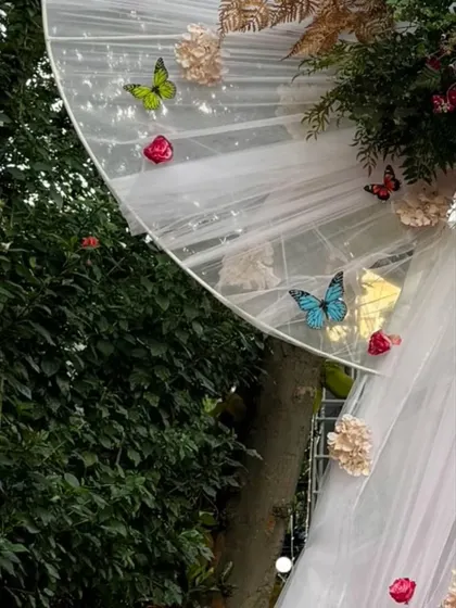 More detail of the delicate butterflies and flowers attached to the white bow entrance, showing the craftsmanship involved in creating these custom pieces.