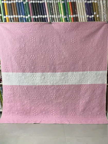 The back of the quilt, featuring a simple design in pink and white.