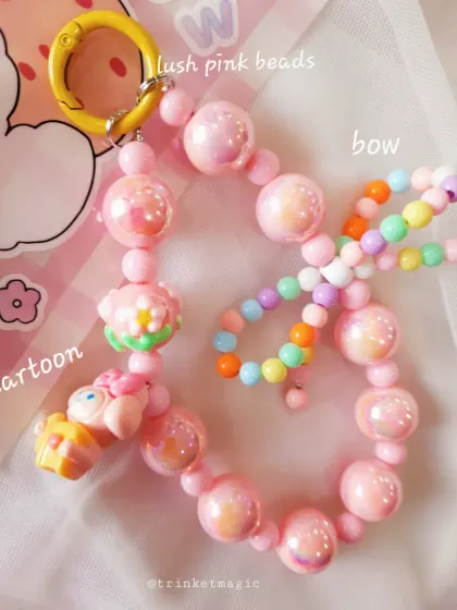 A detailed look at a pink beaded bag charm. I've used lush pink beads, a bow, and cute cartoon charms to create this playful and vibrant piece.
