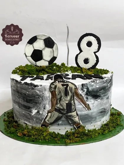 A Ronaldo-themed football cake with a dramatic black and white painted effect. The cake is topped with a 3D soccer ball and the number 8 for the birthday boy.