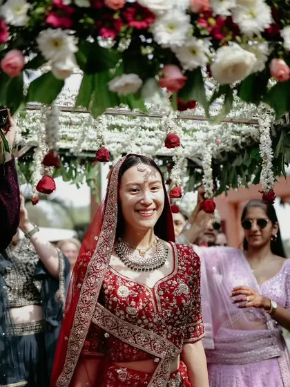 The bride's joyful entrance under a 'phoolon ki chadar' held by her loved ones, a classic and emotional wedding moment.