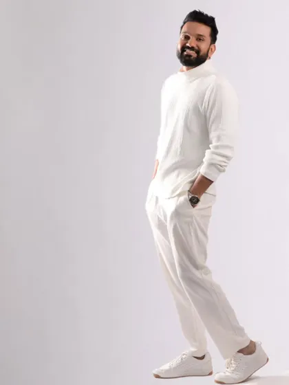 A full-length shot showing the complete all-white look. The grooming contributes to the clean, crisp, and modern aesthetic of the photo.