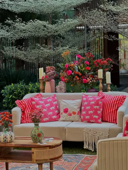 A comfortable sofa is brought to life with a collection of colorful and patterned cushions, surrounded by lush greenery.