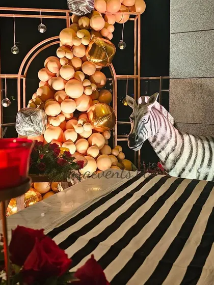 A different angle of the 40th birthday party decor, showing a black and white striped table runner next to a large balloon installation and a zebra prop. This highlights the eclectic and stylish nature of the event.