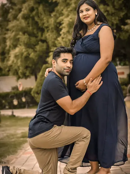 A sweet and tender moment captured during an outdoor couple's session. The dad-to-be kneels to connect with the baby bump, creating a heartwarming memory in a beautiful garden.
