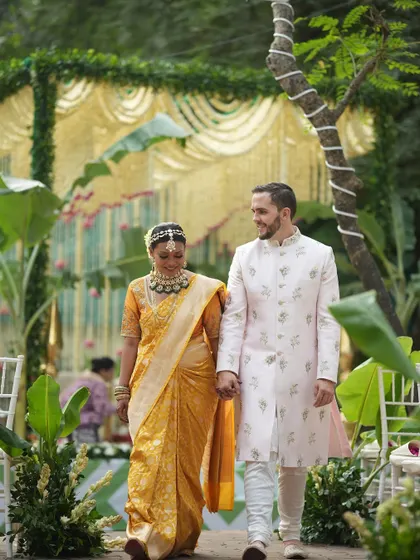 The walk together. Here, the couple makes their way through a path lined with banana plants, a key element in South Indian wedding decor, with a beautiful tuberose mandap waiting for them.