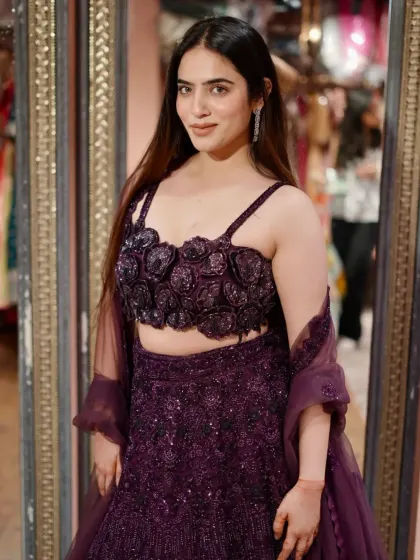 Dripping in glamour. This deep purple lehenga features a stunning 3D floral blouse and an all-over sequin skirt, perfect for a sangeet night.