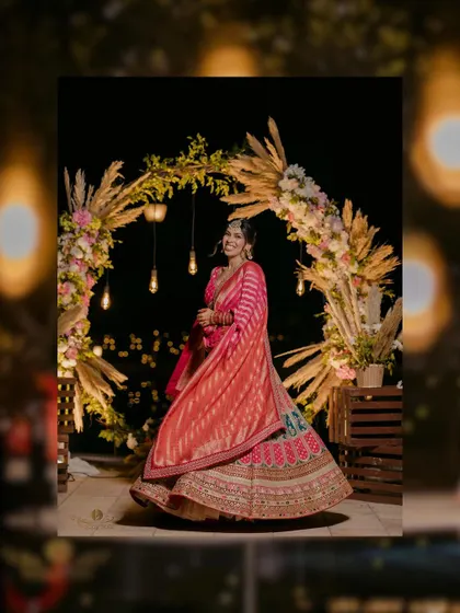 A gorgeous full-length shot of the bride twirling in her multi-colored lehenga against a beautifully lit floral arch.
